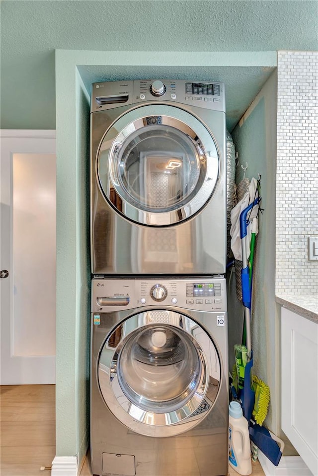 laundry area with stacked washer and dryer, laundry area, and a textured ceiling