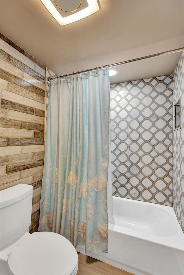 bathroom featuring shower / bath combination with curtain, toilet, and wooden walls