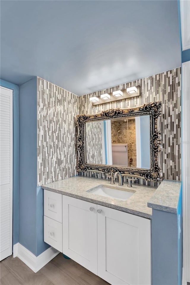 bathroom with tasteful backsplash, tile walls, vanity, and baseboards