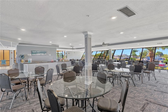 dining room with decorative columns, visible vents, ceiling fan, a textured ceiling, and carpet flooring