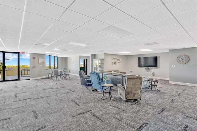 carpeted living room with baseboards and a drop ceiling