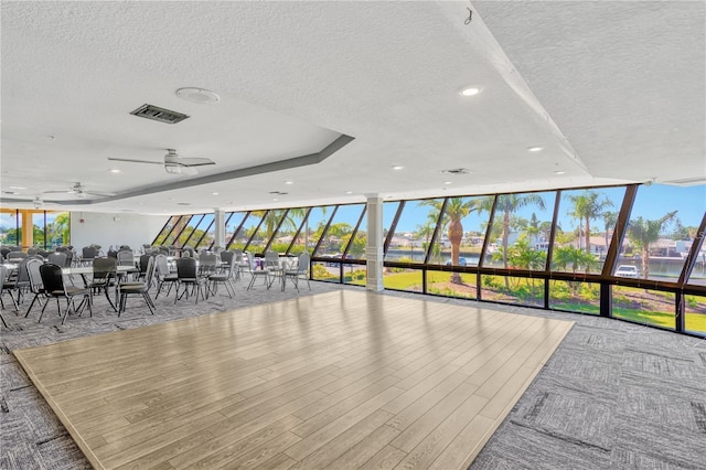 interior space with a wall of windows, visible vents, plenty of natural light, and a textured ceiling