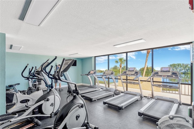 gym featuring plenty of natural light, floor to ceiling windows, and a textured ceiling