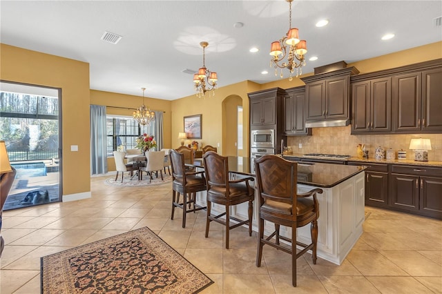 kitchen with visible vents, arched walkways, an inviting chandelier, stainless steel appliances, and backsplash