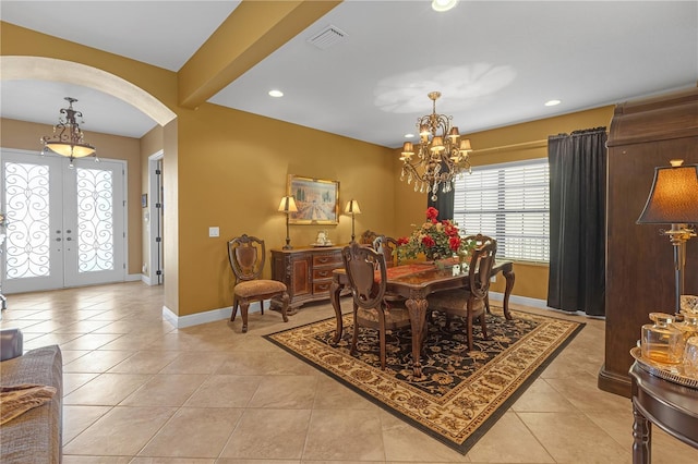 dining area featuring arched walkways, french doors, a notable chandelier, visible vents, and light tile patterned flooring