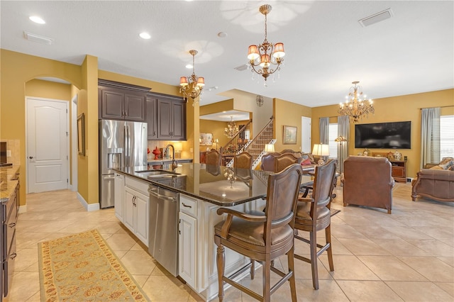 kitchen featuring visible vents, open floor plan, an inviting chandelier, stainless steel appliances, and a sink