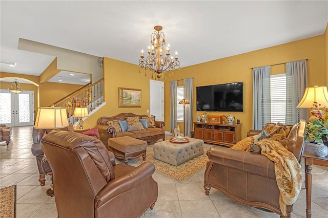 living area with arched walkways, light tile patterned flooring, french doors, stairway, and an inviting chandelier