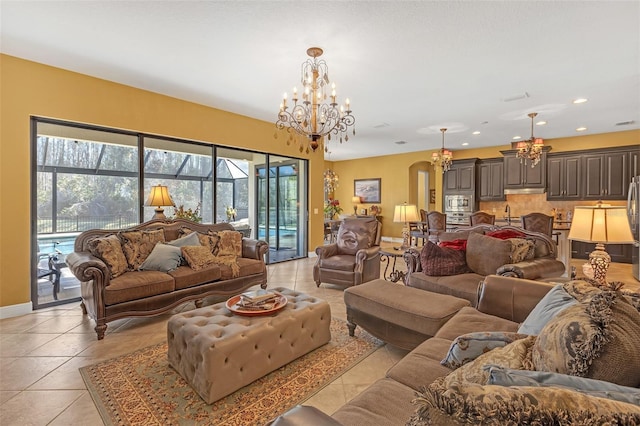 living room featuring arched walkways, light tile patterned floors, recessed lighting, a chandelier, and baseboards