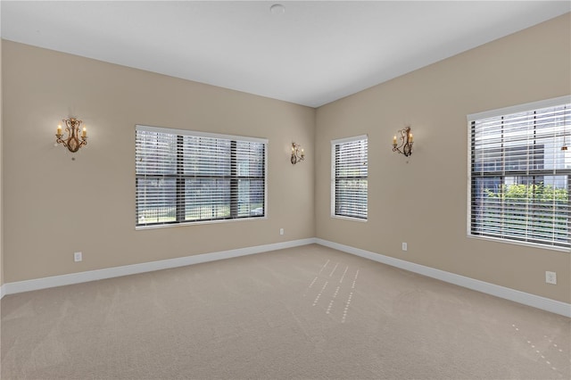 spare room with baseboards and light colored carpet