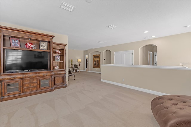 living room with arched walkways, recessed lighting, light colored carpet, visible vents, and baseboards