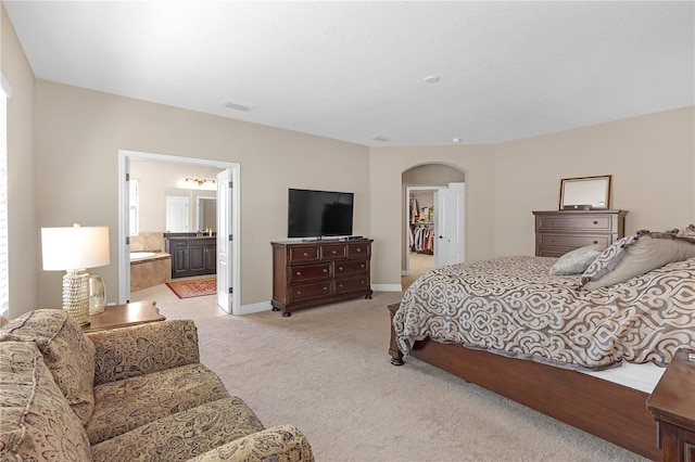 bedroom featuring light carpet, baseboards, arched walkways, visible vents, and a spacious closet