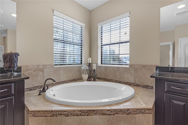 bathroom with visible vents, vanity, and a bath