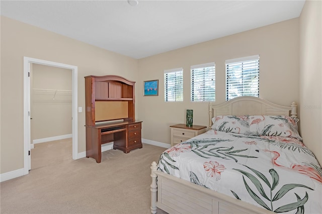 bedroom featuring a closet, light colored carpet, a spacious closet, and baseboards