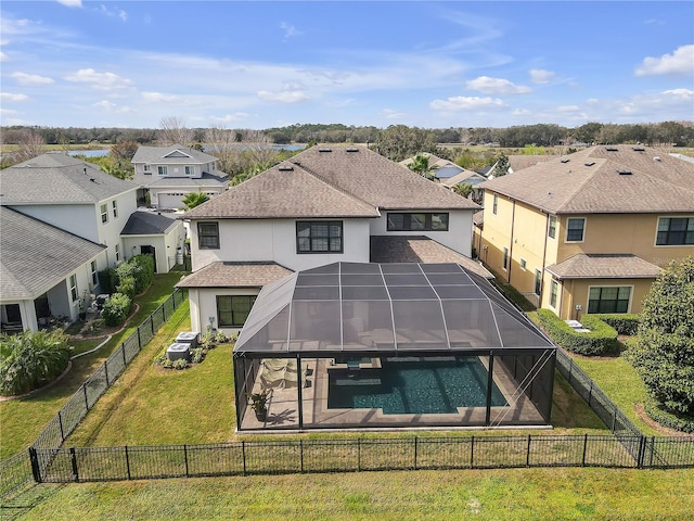 back of property with a yard, glass enclosure, a fenced backyard, and a residential view