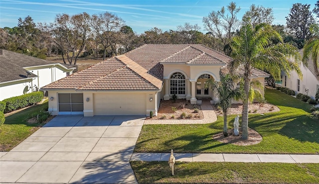 mediterranean / spanish-style home featuring driveway, a tiled roof, an attached garage, a front lawn, and stucco siding