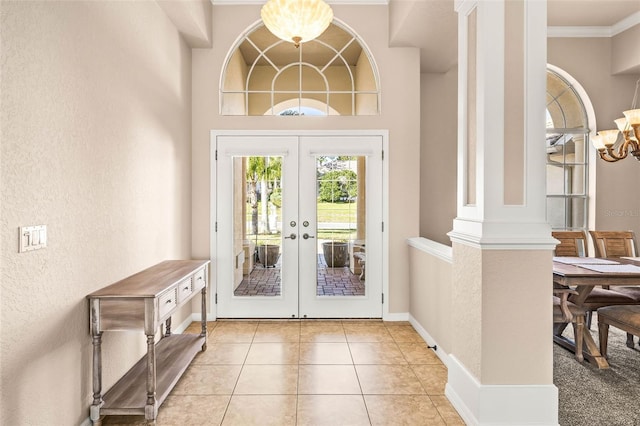 doorway with light tile patterned floors, baseboards, an inviting chandelier, crown molding, and french doors