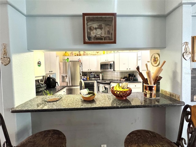 4797 N Lena Dr, Beverly Hills, FL 34465 - kitchen featuring stainless steel appliances, a peninsula, a sink, dark stone countertops, and white cabinetry