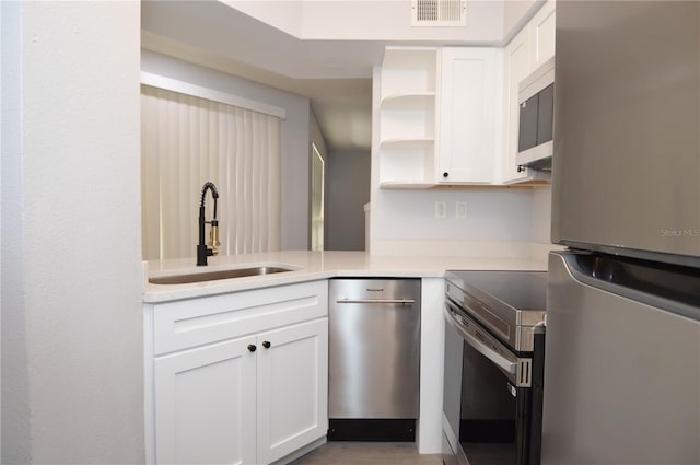 kitchen featuring white cabinets, kitchen peninsula, stainless steel appliances, and sink