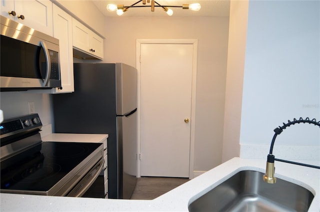 kitchen featuring white cabinetry, stainless steel appliances, a chandelier, sink, and dark hardwood / wood-style floors