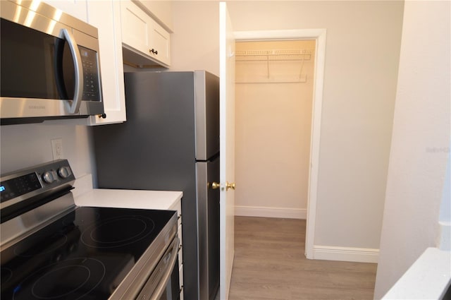 kitchen with white cabinetry, appliances with stainless steel finishes, and light hardwood / wood-style floors