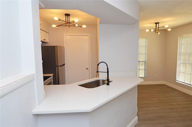 kitchen with sink, pendant lighting, an inviting chandelier, and stainless steel refrigerator