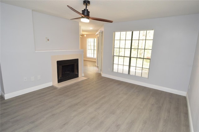 unfurnished living room with a tile fireplace, hardwood / wood-style floors, and ceiling fan