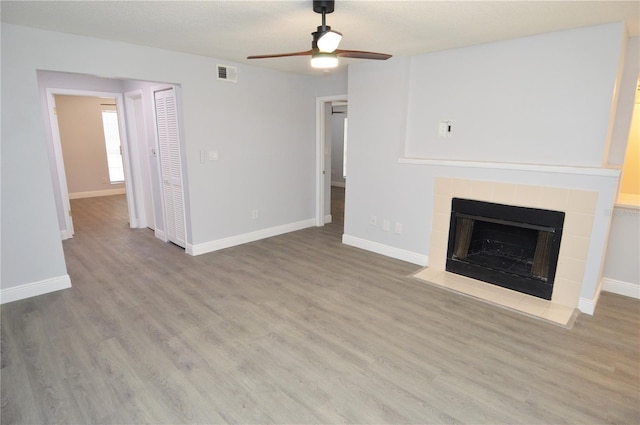 unfurnished living room featuring a fireplace, ceiling fan, and light wood-type flooring