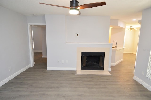 unfurnished living room with hardwood / wood-style floors, ceiling fan, and a fireplace