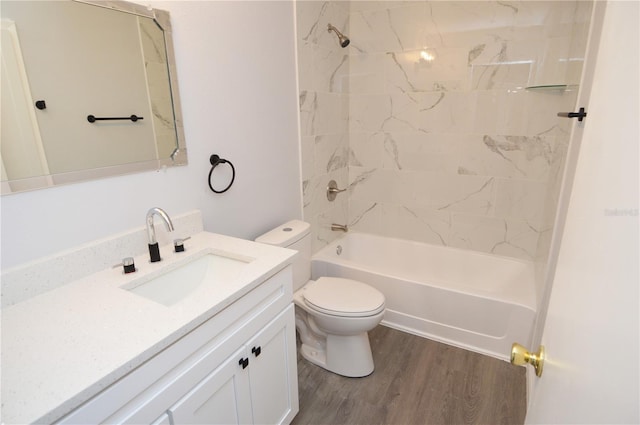 full bathroom with hardwood / wood-style flooring, tiled shower / bath combo, vanity, and toilet