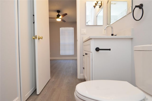 bathroom featuring toilet, vanity, hardwood / wood-style floors, and ceiling fan