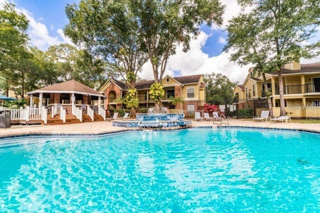 view of pool featuring a gazebo, a hot tub, and pool water feature