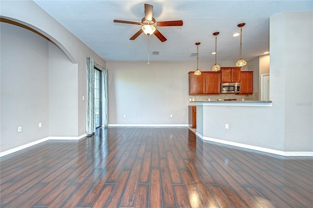 unfurnished living room featuring ceiling fan and dark wood-type flooring