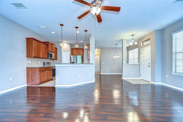 kitchen featuring appliances with stainless steel finishes, dark wood-type flooring, decorative light fixtures, decorative backsplash, and ceiling fan with notable chandelier