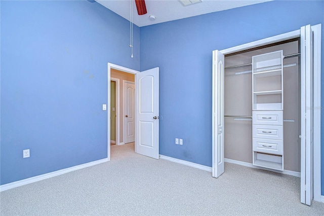 unfurnished bedroom featuring light carpet, a closet, ceiling fan, and a high ceiling