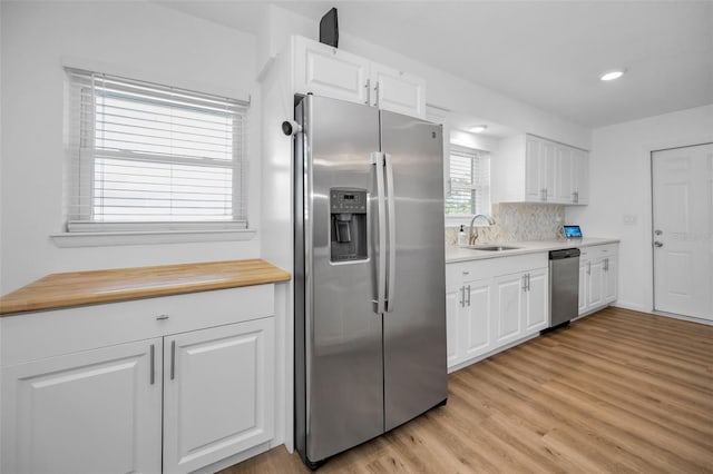 kitchen with white cabinetry, sink, stainless steel appliances, and light hardwood / wood-style flooring