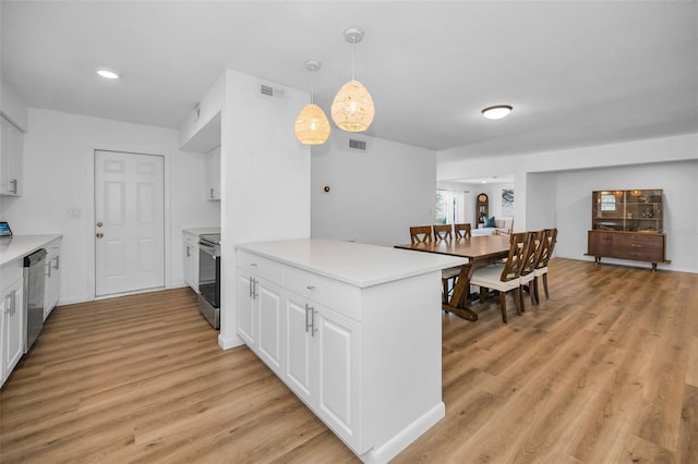 kitchen featuring white cabinets, hanging light fixtures, appliances with stainless steel finishes, and light hardwood / wood-style flooring