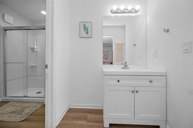 bathroom featuring hardwood / wood-style flooring, a shower with shower door, and vanity