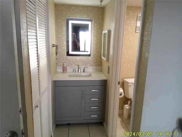 bathroom featuring tile patterned flooring, toilet, vanity, and a closet