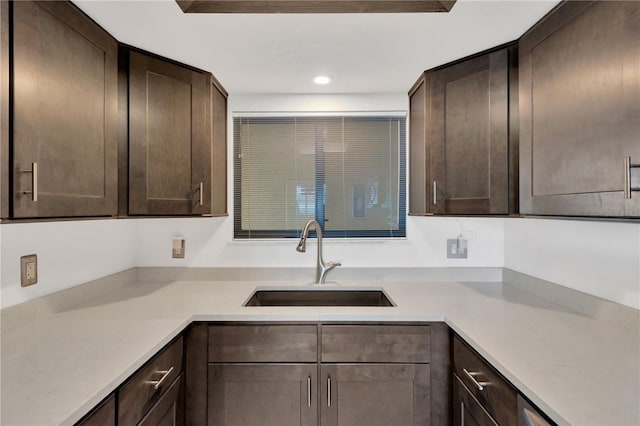 kitchen featuring dark brown cabinetry, recessed lighting, light countertops, and a sink