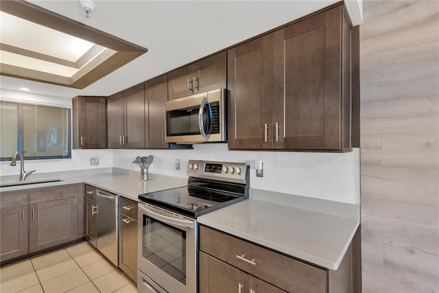 kitchen featuring dark brown cabinets, appliances with stainless steel finishes, light countertops, and a sink