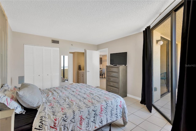 bedroom with light tile patterned flooring, visible vents, a closet, and a textured ceiling