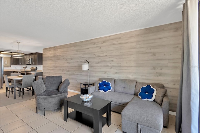 living room with light tile patterned flooring, wood walls, and a textured ceiling