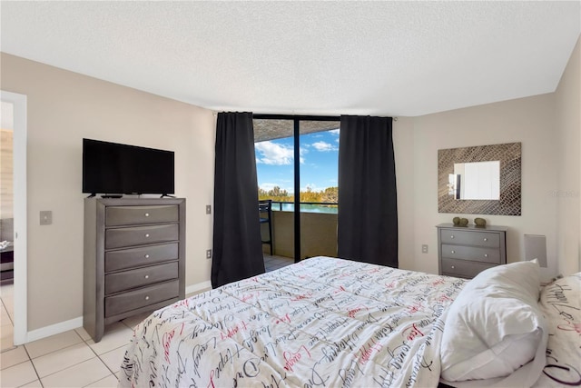 tiled bedroom with access to exterior, floor to ceiling windows, a textured ceiling, and baseboards