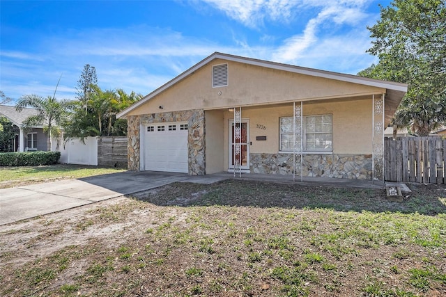 view of front facade with concrete driveway, fence, stone siding, and stucco siding