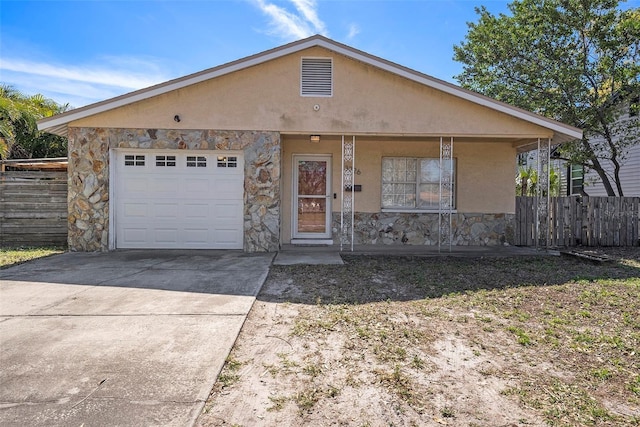 view of front facade with fence, driveway, stucco siding, a garage, and stone siding