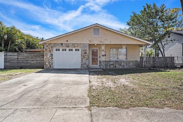 view of front of house with an attached garage, fence, stone siding, driveway, and stucco siding