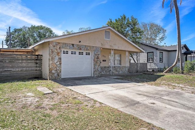 view of front of property with stucco siding, covered porch, a garage, stone siding, and driveway