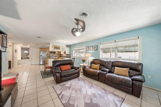 living room with light tile patterned floors, visible vents, and a textured ceiling