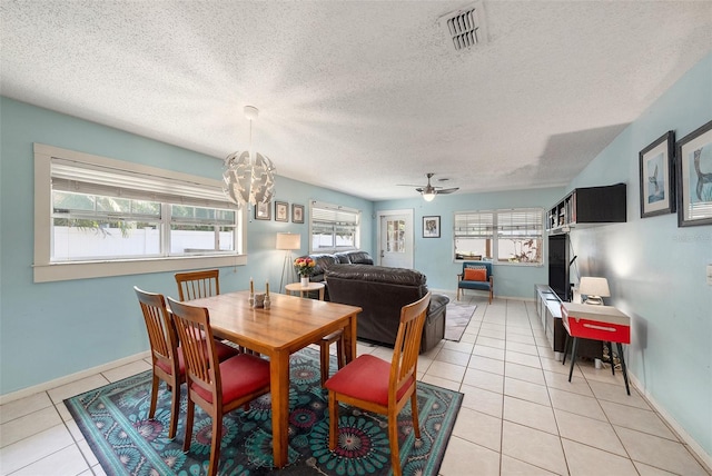 dining room with a textured ceiling, light tile patterned flooring, ceiling fan with notable chandelier, visible vents, and baseboards