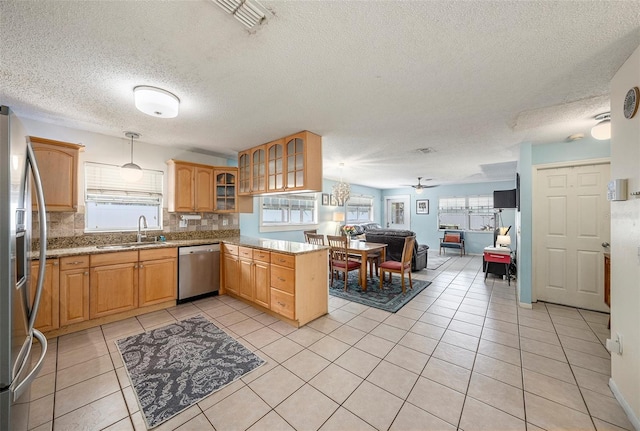 kitchen with open floor plan, decorative light fixtures, a peninsula, stainless steel appliances, and a sink